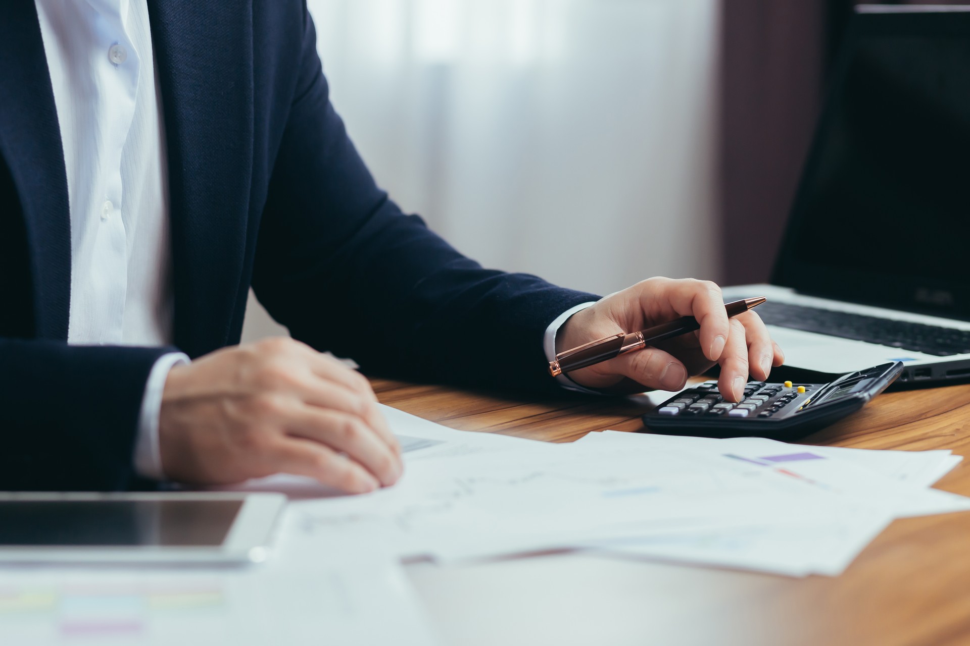 Close-up photo, businessman accountant's hand counts on a calculator, man sitting at a table paperwork